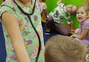 Zuzia bada Jasia stetoskopem.
