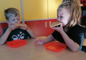 Maja i Kajtek jedzą wafle z jabłuszkami.