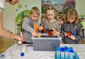 Mali ogrodnicy samodzielnie napełniają doniczki ziemią.