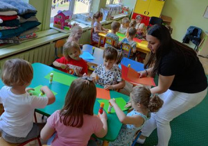 Zaproszony gość rozdaje materiały do wykonania pracy plastycznej.