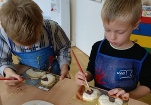 Antoś i Jaś ozdabiają swoje pieczywo.