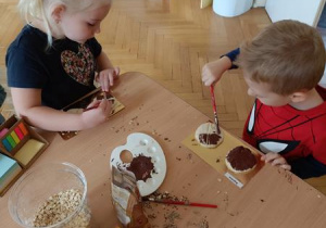 Bogusia i Kajtek malują swoje pieczywo farbami.