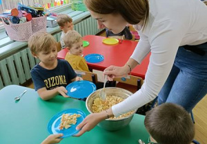 Ciocia Karolina częstuje dzieci sałatką.