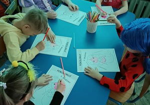 Przedszkolaki kolorują obrazek przedstawiający Małą Syrenkę.