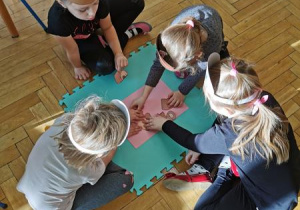 Dzieci układają misia z puzzli.