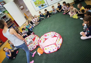 Dzieci siedzą na dywanie i słuchają ciekawostek o zwierzętach.