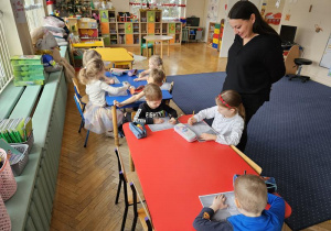 Pani Aneta podziwia pracę dzieci przy stolikach.