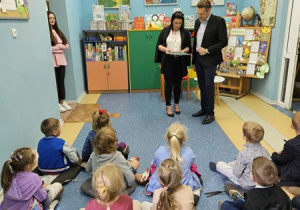Przewodniczący Rady Miasta Skierniewice wybiera książkę, którą przeczyta przybyłym przedszkolakom.