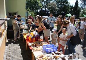 Zaproszeni goście stoją przy stoisku kulinarnym