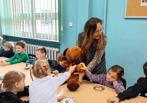 Pani bibliotekarka pokazuje dzieciom pluszowego misia