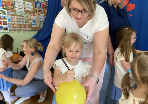 Marysia i jej mama ozdabiają balon.