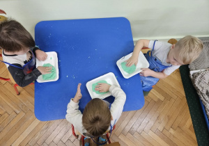 Zabawa z masą solną przy niebieskim stoliku.