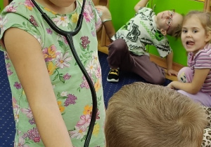 Zuzia bada Jasia stetoskopem.