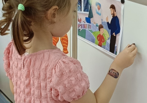 Blanka przywiesza obrazki na tablicy.