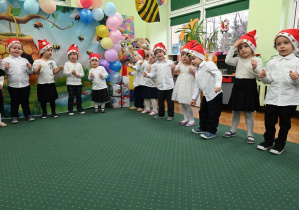 Piosenka o Świętym Mikołaju z wykorzystaniem czerwonych czapek.
