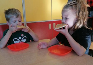 Maja i Kajtek jedzą wafle z jabłuszkami.