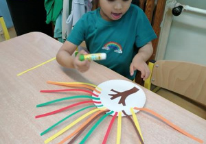 Apolonia przykleja kolorowe paski.