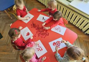 Wyklejanie serduszek przy stoliku.