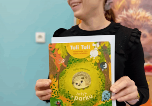 Pani bibliotekarka z książką pt. "Jeżyk w parku".