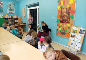 Pani bibliotekarka czyta dzieciom książkę o przygodach małego jeżyka.