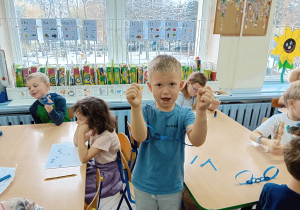 Chłopiec prezentuje kajdanki z papieru.