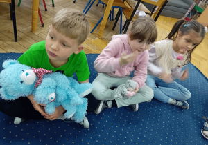 Dzieci siedzą w kole ze swoimi pluszowymi misiami.
