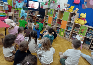 Przedszkolaki oglądają prezentację na temat historii powstania pluszowego misia.