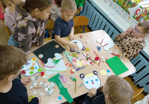 Dzieci ozdabiają materiałami kreatywnymi swoje misie z papieru.