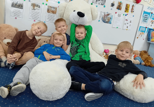 Dzieci z białym, pluszowym misiem.