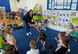 Wolontariuszka przedstawia dzieciom psa ze schroniska.