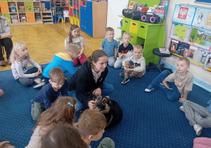 Dzieci głaszczą pieska ze schroniska.