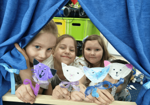 Dziewczynki prezentują swoje kotki z papieru.