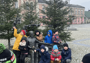 Dzieci pozują do zdjęcia obok ławeczki prof. Pieniążka.