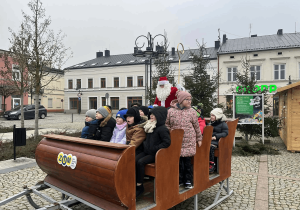 Dzieci siedzą w saniach Św. Mikołaja.