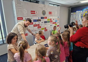 Pan Konrad zdradza dzieciom tajniki pracy z mikrofonem podczas medialnych spotkań.