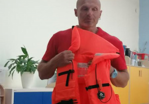 Ratownik prezentuje kamizelkę ratunkową.