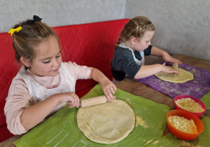 Dziewczynki szykują swoje spody od pizzy.