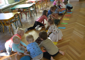 Przedszkolaki dotykają różnych faktur ścieżki sensorycznej za pomocą rączek.