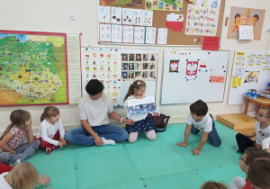 Hania pokazuje dzieciom ilustracje w książce.