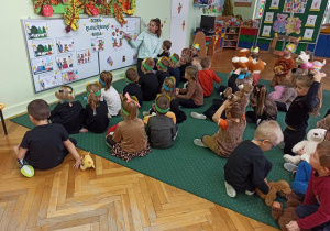 Przedszkolaki słuchają, jak prawidłowo wykonać pluszowego misia.